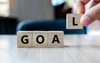 businesswoman-hand-holding-wooden-cube-with-goal-