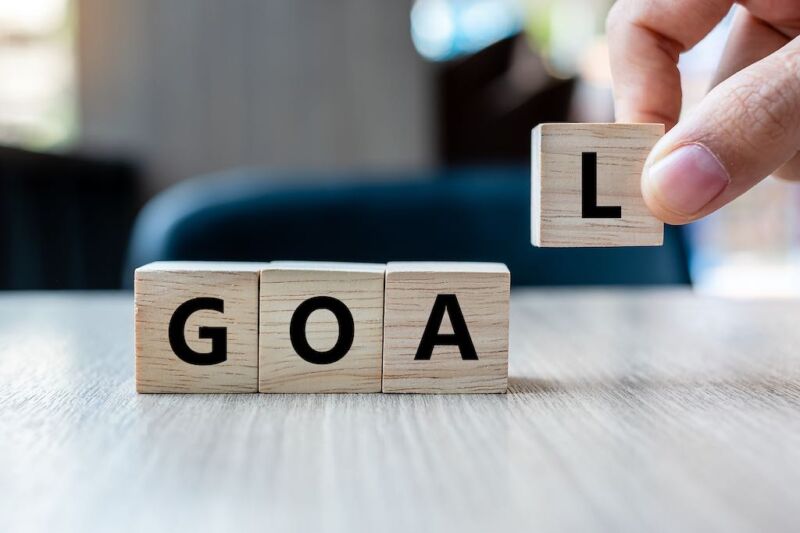 businesswoman-hand-holding-wooden-cube-with-goal-